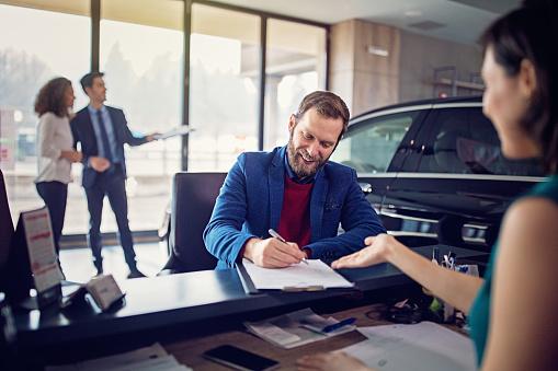 Man is buying new car and signing the contract