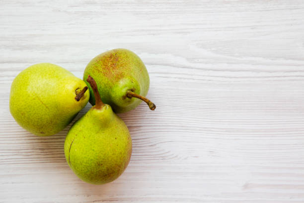 istock Fresh pears on a white wooden table, top view. Copy space. 1015042792