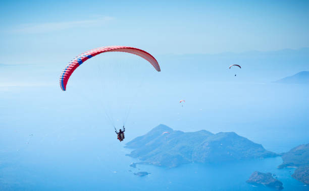 istock Parachute skydiver flying in clouds at top of mountains 1015045192