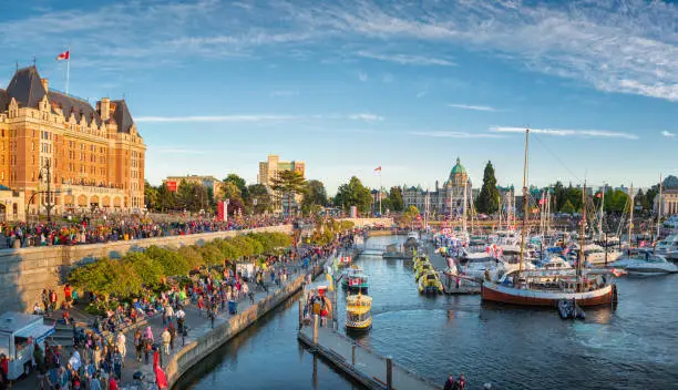 Canada Day in Victoria, Vancouver Island, Canada. Masses of people visiting the celebrations at inner harbour with the parliament building during sunset.