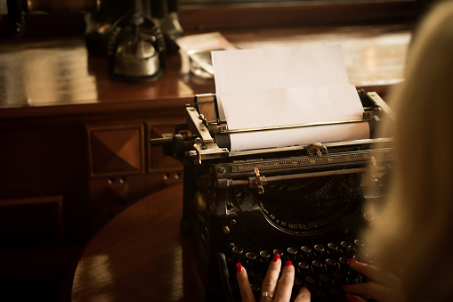 In front of her is a typewriter and empty paper, she is ready to write a new article for the new edition of the newspaper.