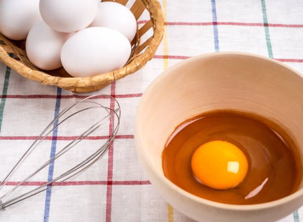 istock Bowl with egg yolk, a wooden basket with eggs and a hamper for beating on the table 1015067680