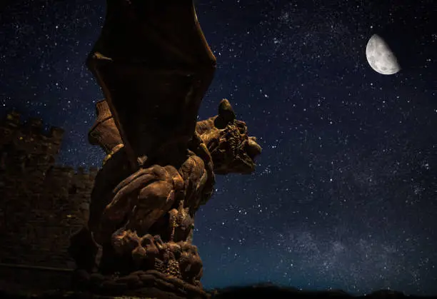 gargoyle statue against moon lit night sky
