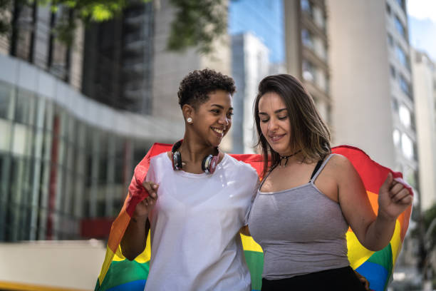 Lesbian Couple with Walking Rainbow Flag Gay Couple lgbtqia pride event photos stock pictures, royalty-free photos & images