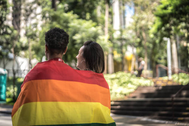 Lesbian Couple with Walking Rainbow Flag Gay Couple lgbtqia pride event photos stock pictures, royalty-free photos & images