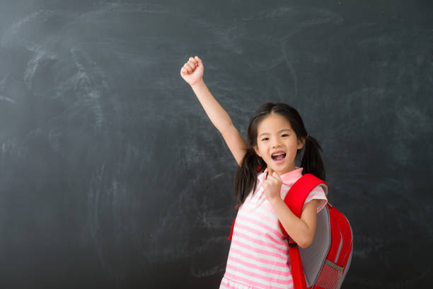 istock little girl standing in blackboard background 1015117538