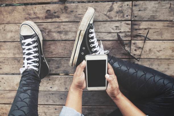 istock Woman using smart phone on hand and sneakers 1015130698