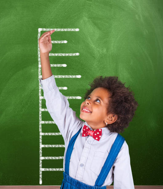 istock African schoolgirl is showing height on a blackboard scale 1015133888