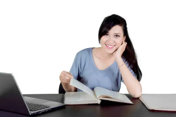 Picture of Caucasian female college student smiling at the camera while studying in the studio