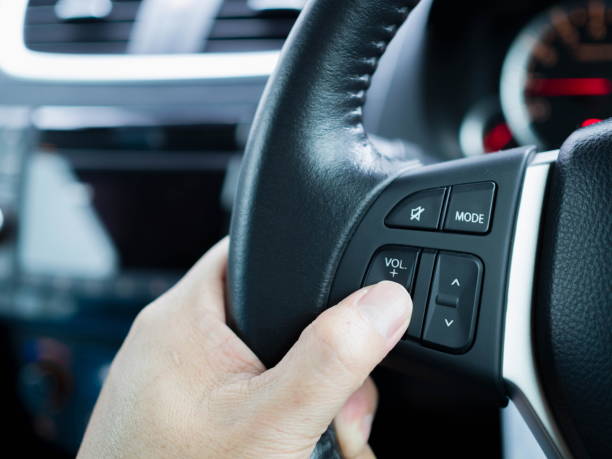 istock Close up driver's hands press volume button on a steering wheel 1015180734