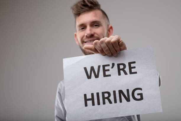 istock Smiling man holding up a sign We're Hiring 1015185930