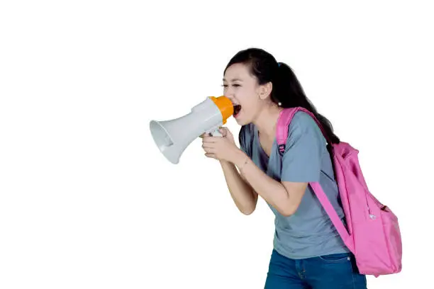 Picture of Caucasian college student carrying a bag while using a megaphone to speak at the camera
