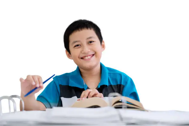 Picture of little boy smiling at the camera while taking notes in the studio, isolated on white background