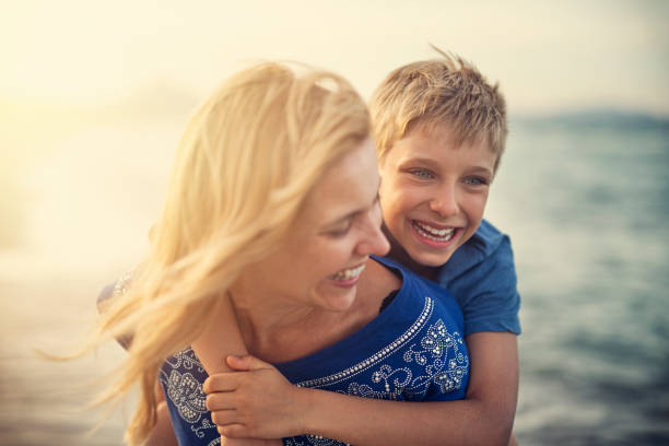 istock Mother giving son piggyback ride on beach 1015206912