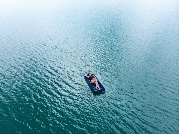 istock woman on mattress in azure water. overhead view. copy space 1015209590