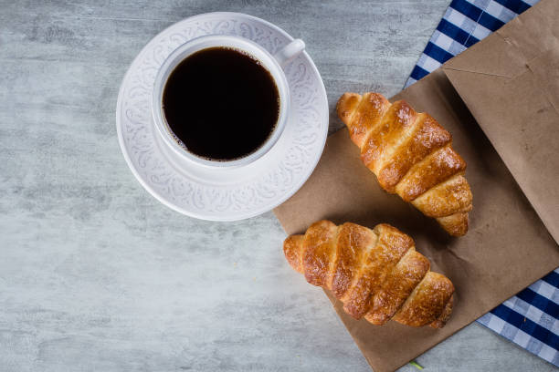 istock Cup of black coffee with croissants on grey table background. 1015217618