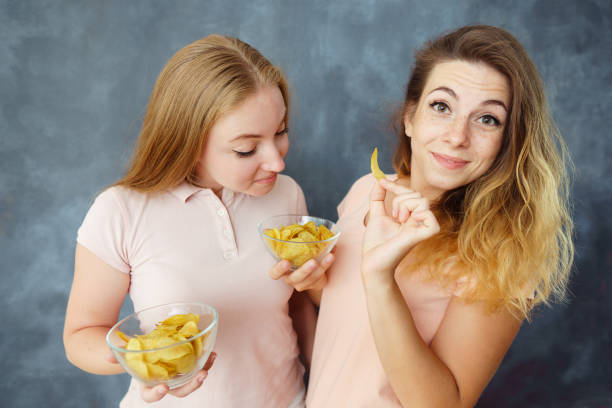 istock Cute young women enjoy eating potato chips 1015229270