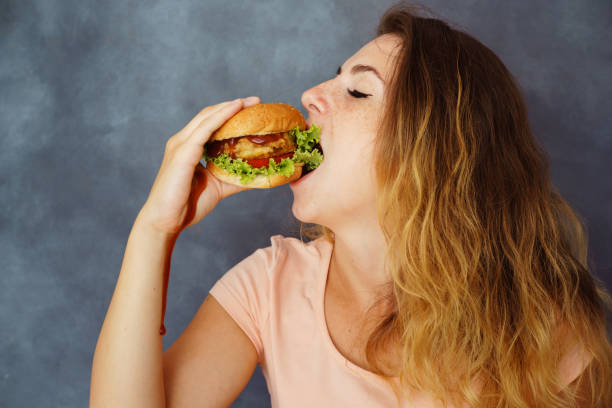 istock woman eating burger smearing hands with sauce 1015229352