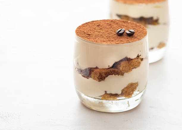 Classic tiramisu in a glass on a white background. Copy space. Classic tiramisu in a glass on a white background. tiramisu glass stock pictures, royalty-free photos & images