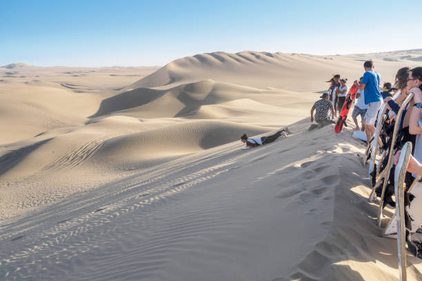 Huacachina, Peru - Oct 2, 2017: Tourists are joining the most famous tour, the sandboarding.