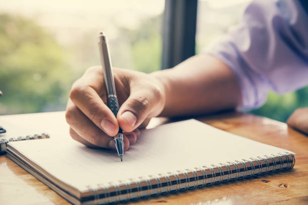 istock Close up image of man hand writing on notebook with wooden table background 1015232966