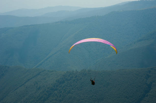 istock Paraglider flies over a mountain valley on a sunny summer day. 1015238448