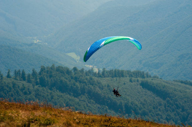 istock Paraglider flies over a mountain valley on a sunny summer day. 1015240280
