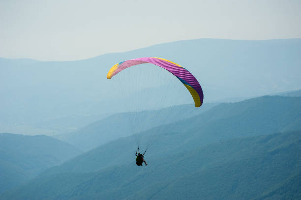 istock Paraglider flies over a mountain valley on a sunny summer day. 1015240292
