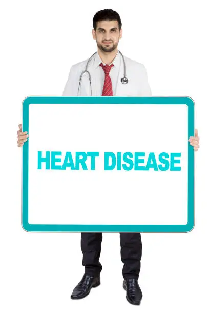 Arabian male doctor holding a board with heart disease text, isolated on white background