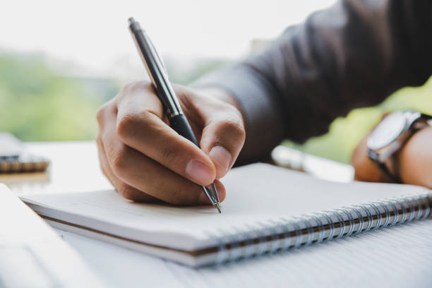istock Close up image of man hand writing on notebook with wooden table background 1015250140