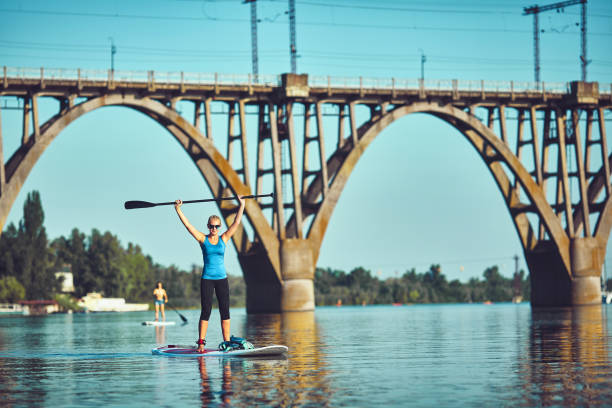 istock SUP Stand up Surf girl with paddle at sunset 1015252890