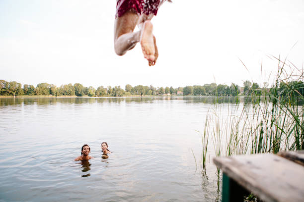 día de verano: tres jóvenes saltan de embarcadero en el lago - jumping freedom women beach fotografías e imágenes de stock
