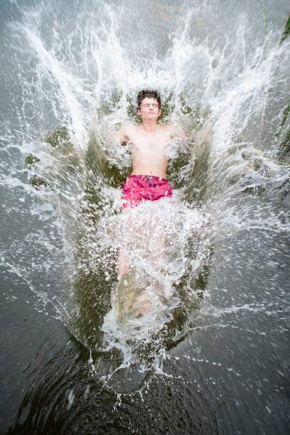 young man jumps backwards into a lake, water splashes around young man jumps backwards into a lake, water splashes around person falling backwards stock pictures, royalty-free photos & images