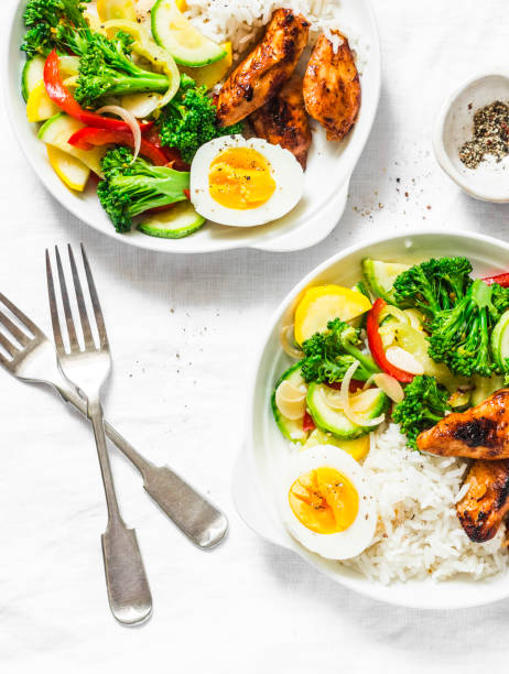 Lunch served - stewed vegetables, rice, boiled egg and teriyaki chicken on light background, top view