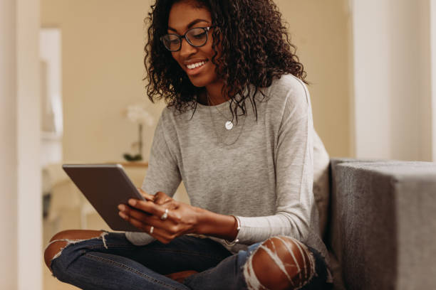istock Woman using tablet pc sitting at home 1015263450