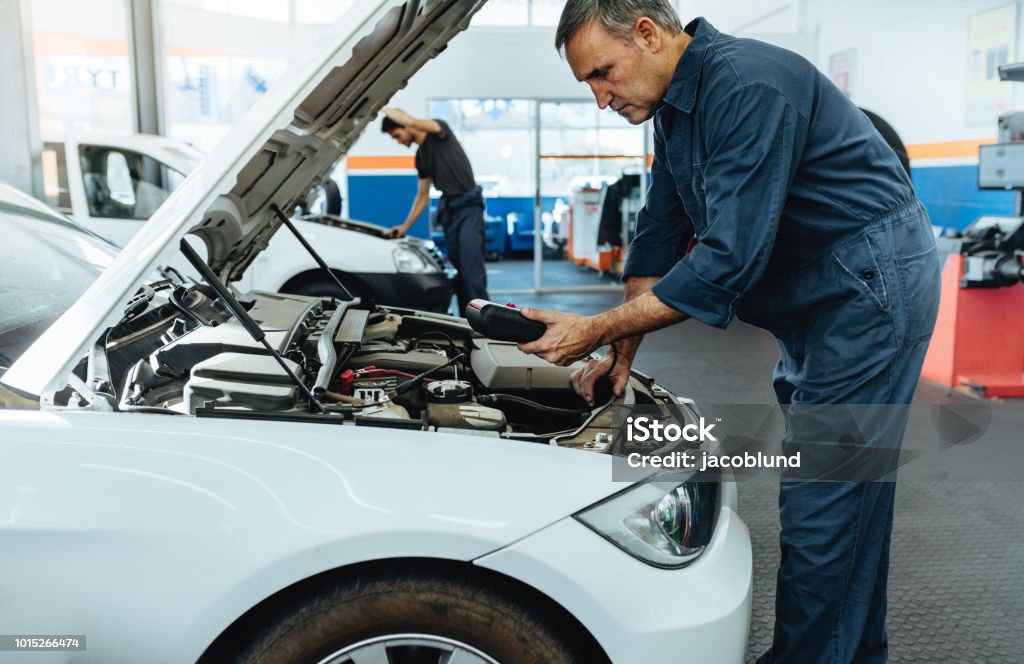 Mechanic reading the error codes with diagnostic device Car mechanic with diagnostic device for reading the error codes. Mechanic checking the car in service station. Auto Repair Shop Stock Photo