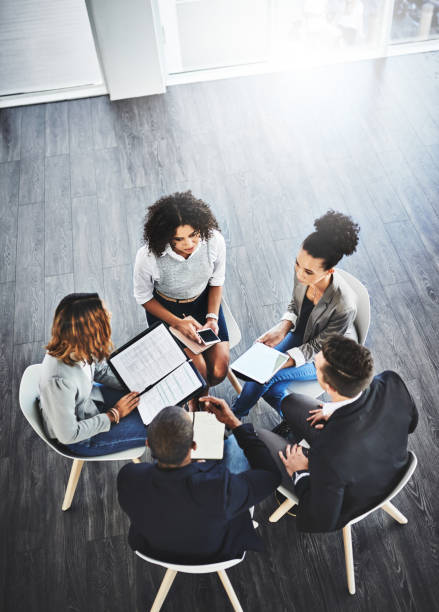 They have some big plans to manage together High angle shot of a group of businesspeople having a discussion in an office business activity stock pictures, royalty-free photos & images