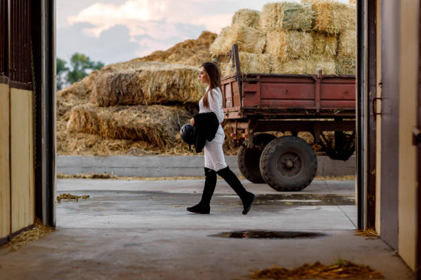 istock rider woman walks past stable after training 1015270330