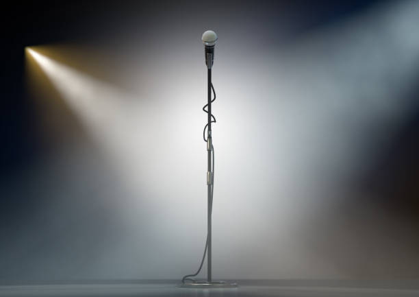 Microphone Stand On Stage A dark stage with a single microphone on a stand dramatically lit by two spotlights - 3D render microphone stand stock pictures, royalty-free photos & images
