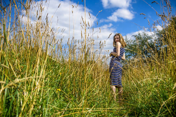 istock Beautiful young woman walking through a meadow against a blue sky with clouds 1015280258