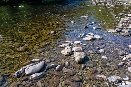 Stones and rocks on the bank of shallow stream on midday