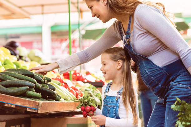 la madre incinta e sua figlia comprano verdure - organic farmers market market vegetable foto e immagini stock