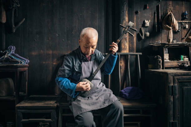 chinese senior man playing longneck lute indoors