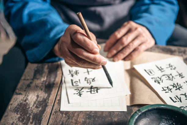istock chinese senior man writing chinese calligraphy characters on paper 1015284524