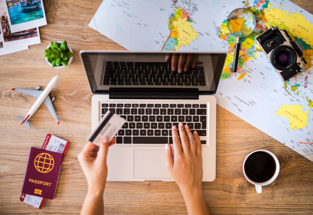 Buying tickets and making reservation for travel with credit card Hand holding a credit card and using laptop and making a reservation for travel. discover card stock pictures, royalty-free photos & images
