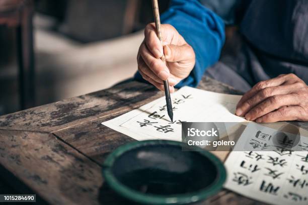 Chinese Senior Man Writing Chinese Calligraphy Characters On Paper Stock Photo - Download Image Now