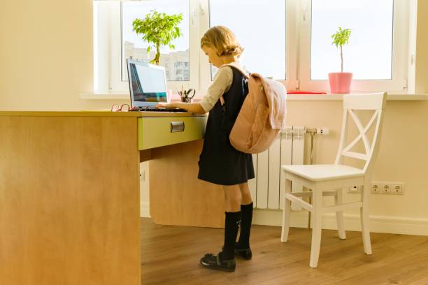 la bambina di 8 anni in uniforme scolastica con uno zaino usa il laptop. scuola, istruzione, conoscenza e bambini. - 6 7 years little girls child portrait foto e immagini stock