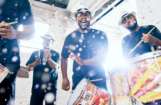 Low angle portrait of a group of handsome young male drummers playing at Carnival