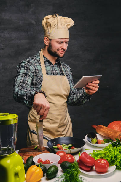 istock Bearded male chef cook looking in the tablet PC. 1015296568