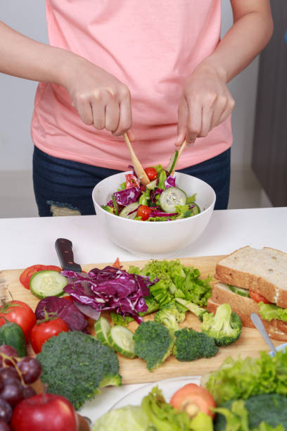 istock close up woman mixing salad while cooking in kitchen 1015301738